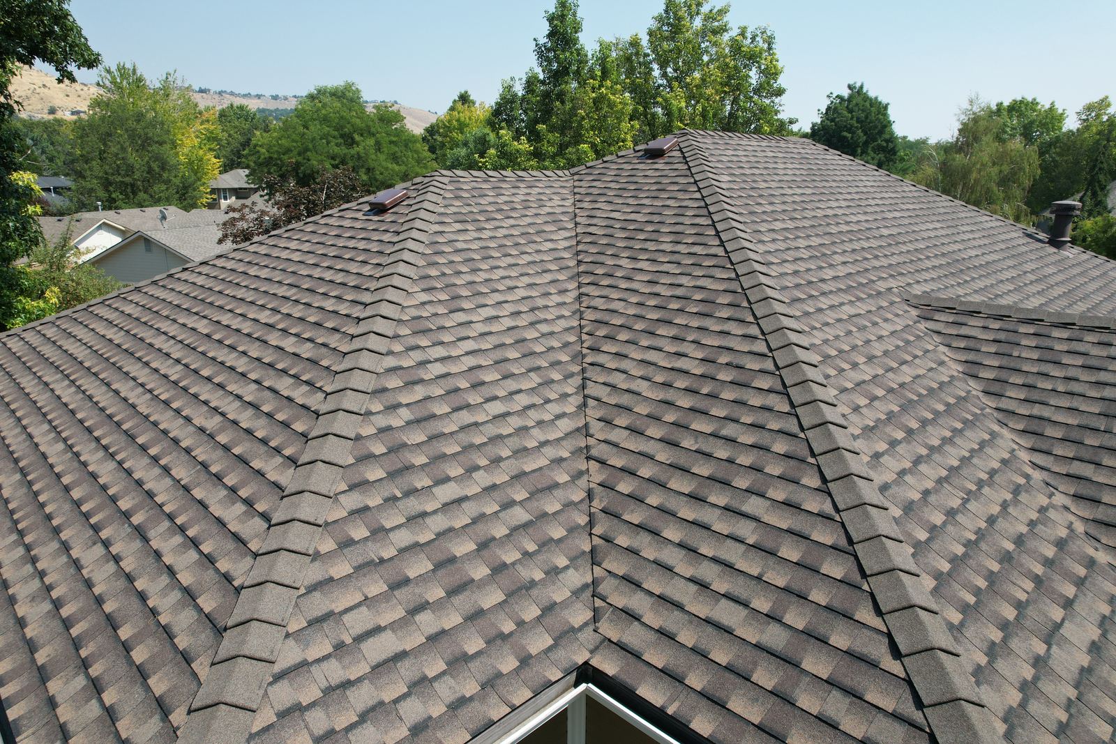 Close view of a finished brown asphalt shingle roof with ridge caps and two skylights in Boise, installed by Bork Roofing.