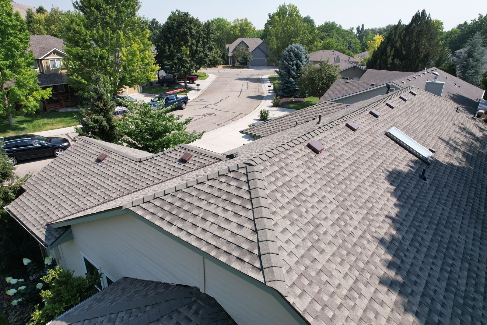 High angle view of a finished tan asphalt shingle roof with ridge vents on a house in Boise, installed by Bork Roofing.