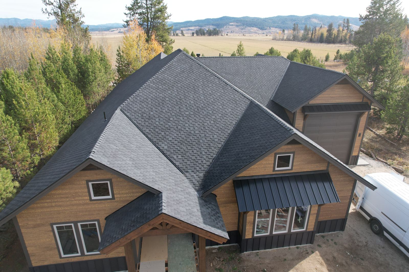 Aerial view of a charcoal asphalt shingle roof on a wood sided home in Donnelly, Idaho, installed by Bork Roofing.