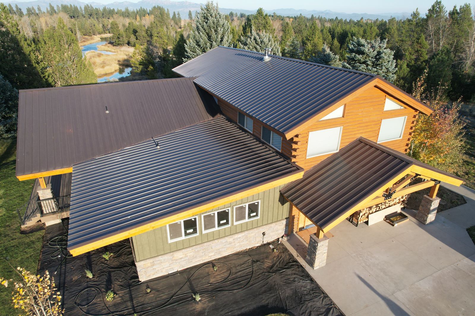 Dark brown standing seam metal roof on a log and timber home in McCall, Idaho, installed by Bork Roofing.