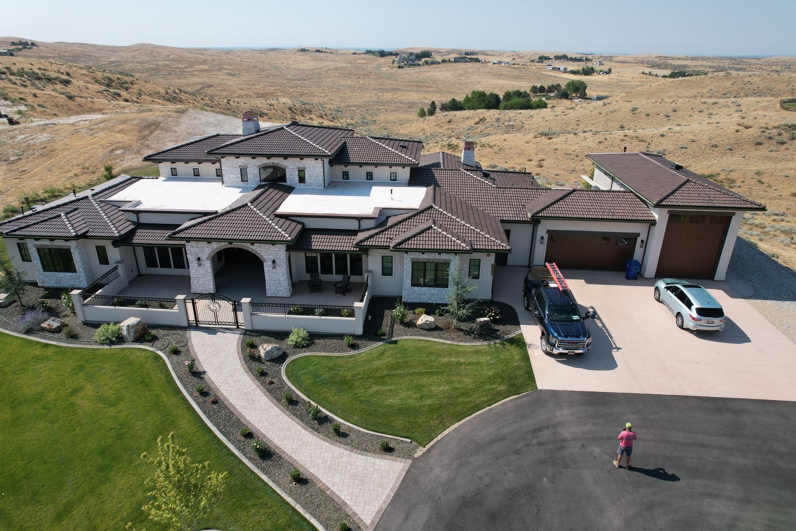 Brown concrete tile roof with white flat roof sections on a large stucco and stone home in Star, Idaho, installed by Bork Roofing.