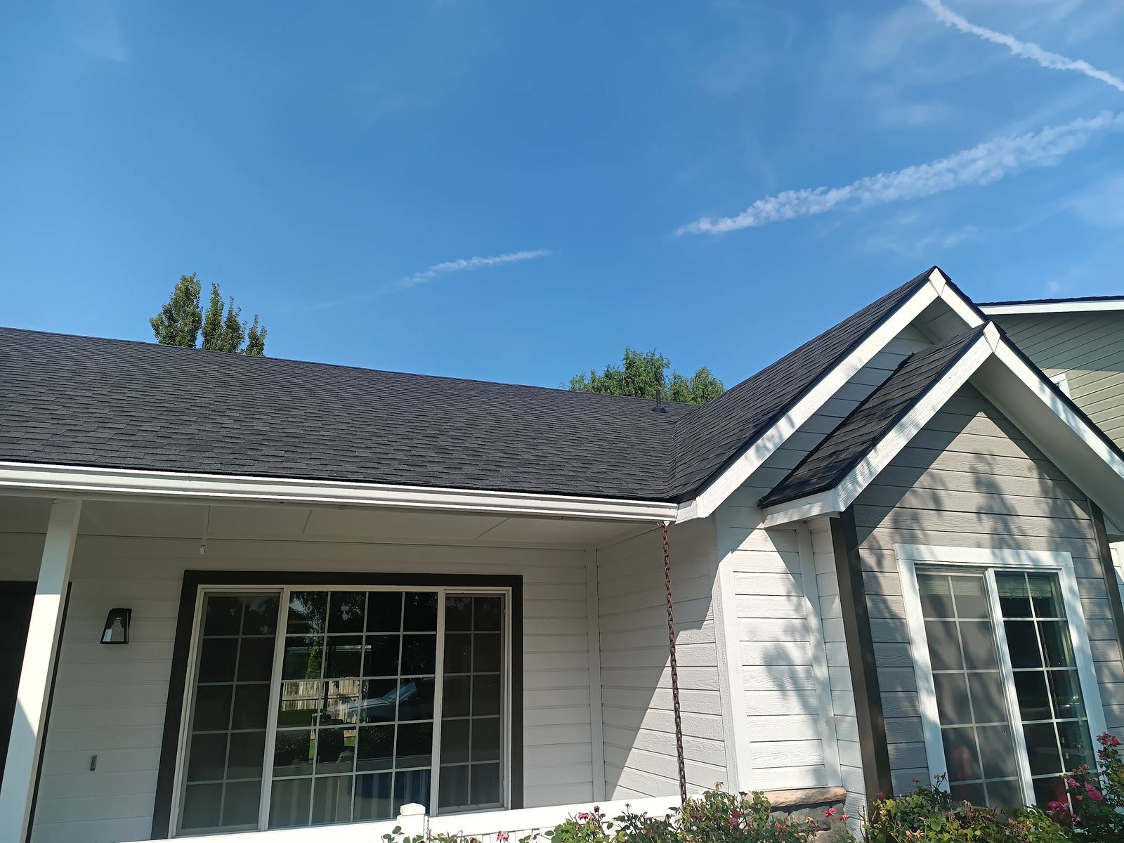New dark gray asphalt shingle roof on a single story house with white siding in Nampa, installed by Bork Roofing.