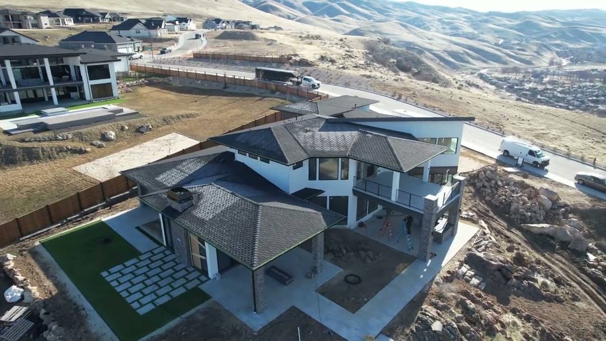 Charcoal GAF Grand Sequoia shingles with black standing seam metal on the lower roofs of a hillside home